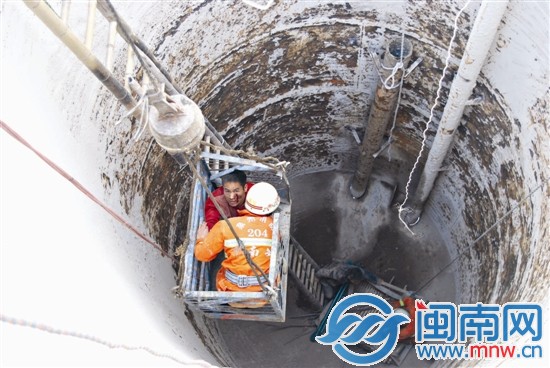 吊机将受伤工人和消防队员吊出污水处理罐