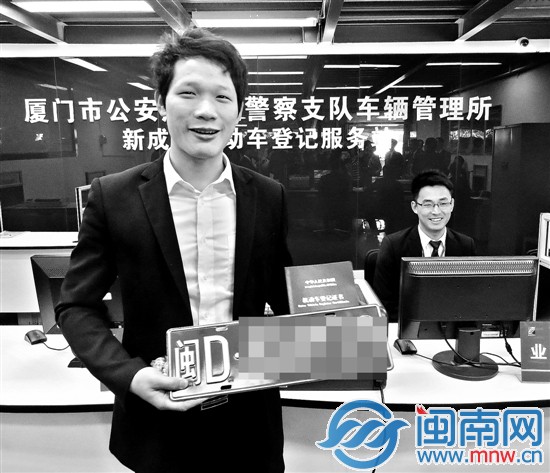 一名买车的顾客在4S店领取新车牌证