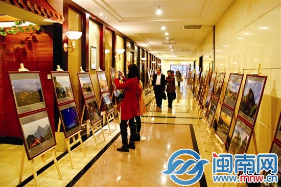 摄影展上，市民用相机拍下照片中的美景