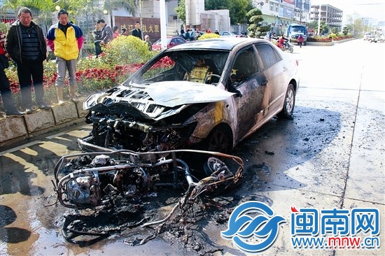 火被扑灭后，小车前躺着一辆被烧得只剩钢架的助力车