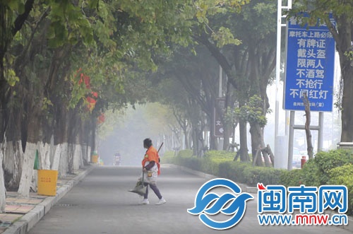 一名环卫工在雾中清扫