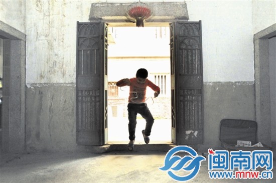 小斌一个人在房门口玩着胶带，仿如孤独的舞者