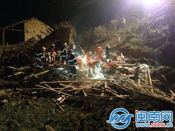 两层民房坍塌后，消防官兵在现场挖开梁木泥土，救出