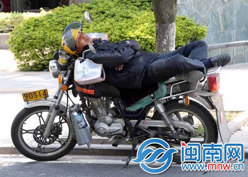 一载客的摩的师傅躺在摩托车上睡着了