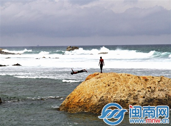 加勒海边玩跳水的少年一遍遍跳入水中