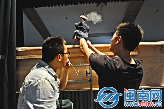 先吸一口烟,再通过塑料管吹到前台木偶手里的烟斗上去