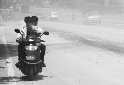 摩托车司机只能一手捂着口鼻,一手抓着扶手,快速闯