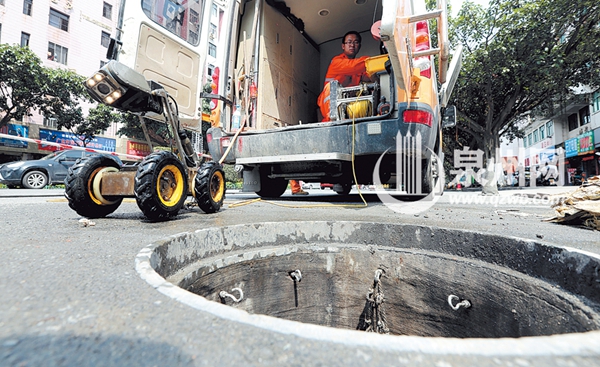 工作人员正在操作机器人检查地下排污管道
