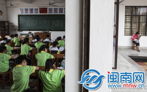 儿子在教室内上课,母亲怕自己睡着,在教室外钩着毛