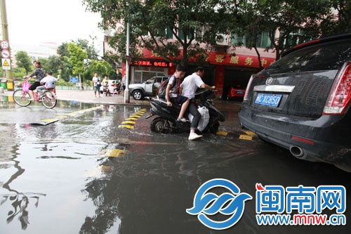 一名男子载着孩子经过这里，陷在坑里