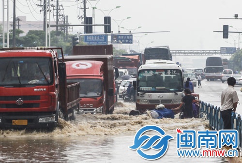 南环路上积水太深，摩托车在路中抛锚，市民躲上隔离栏