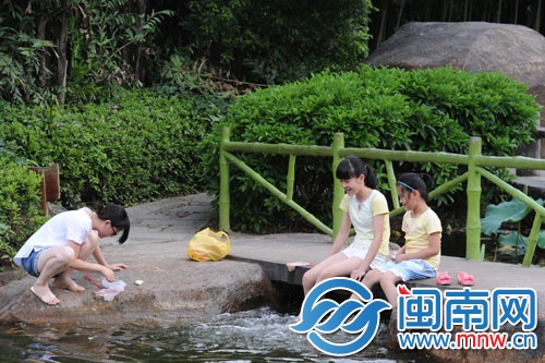 天气太热,坐在水边玩水,让脚凉快些