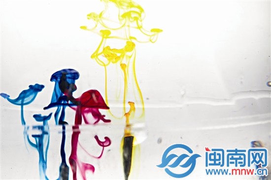 画笔刚接触水面，颜色在透明的水里散开，像是一只只