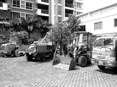 多辆工程车停放在小区公共绿化带。