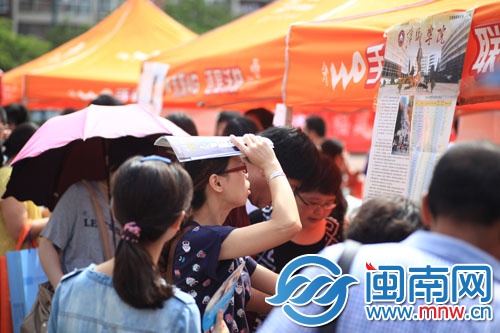 海都咨询会现场，一名家长顶着烈日看学校信息
