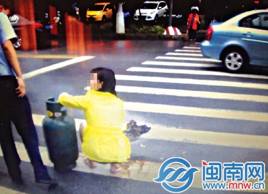 晋江市标附近，女子蹲在人行道用煤气罐烧纸，被民警 