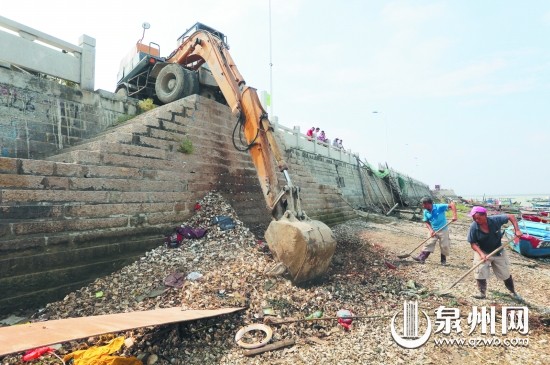 几名工人正在配合挖掘机清理河道内的垃圾