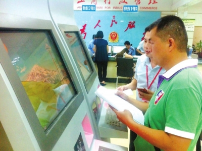 工作人员指导李建才在终端机上填写材料。